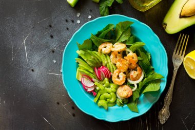Izgara karides, rucola, turp, avokado, kereviz ve salata sosu karanlık arduvaz arka plan üzerinde sağlıklı sebze salatası. Diyet menüsü. Üst görüntülemek düz yatıyordu arka plan. Kopya alanı.