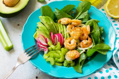 Izgara karides, rucola, turp, avokado, kereviz ve salata sosu ışık arduvaz arka plan üzerinde sağlıklı sebze salatası close-up. Diyet menüsü.