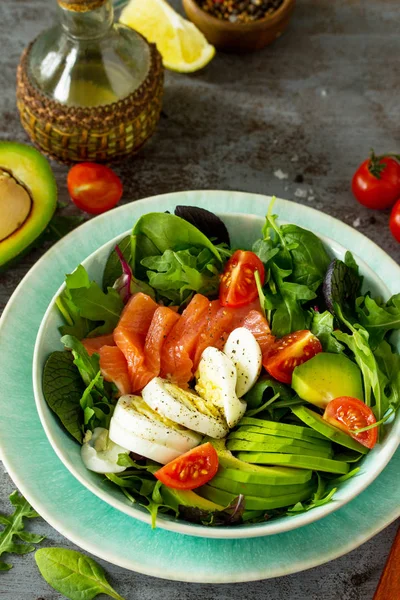 Diet menu concept. Summer Healthy salad with Tomatoes, Salmon, Egg, Avocado and arugula on a dark stone table. Copy space.