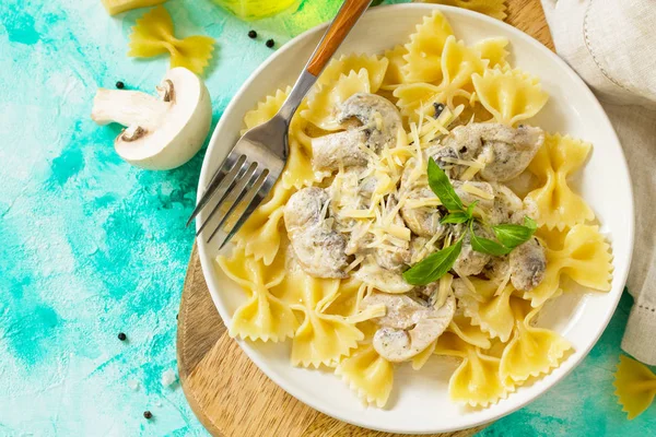 Pasta farfalle with mushrooms and cheese on blue stone table. Ve — Stock Photo, Image