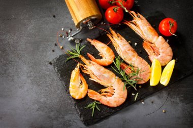 Deniz ürünleri. Bir kayrak b üzerinde baharat, domates ve limon ile Çiğ karides