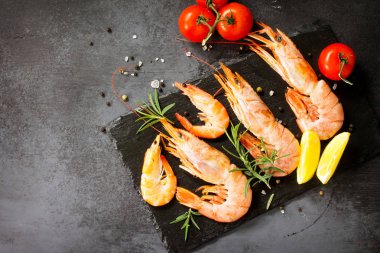 Deniz ürünleri. Bir kayrak b üzerinde baharat, domates ve limon ile Çiğ karides