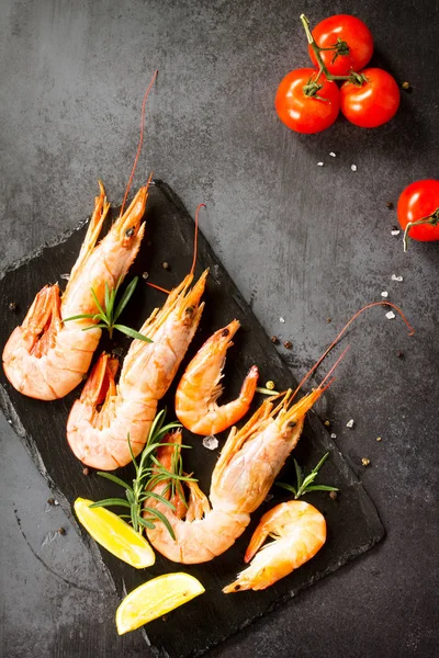 Zeevruchten. Rauwe garnalen met specerij, tomaten en citroen op een leisteen b — Stockfoto