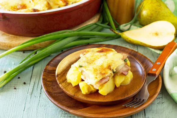 Potato gratin with pear, raclette cheese, and bacon on rustic wo — Stock Photo, Image