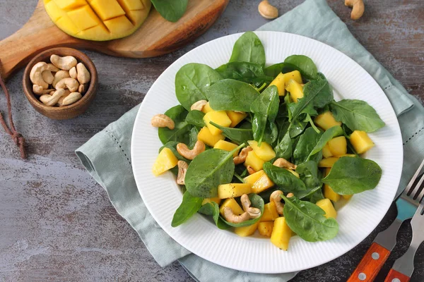 Diet menu, Vegan food. Healthy salad with spinach, mango, pecan