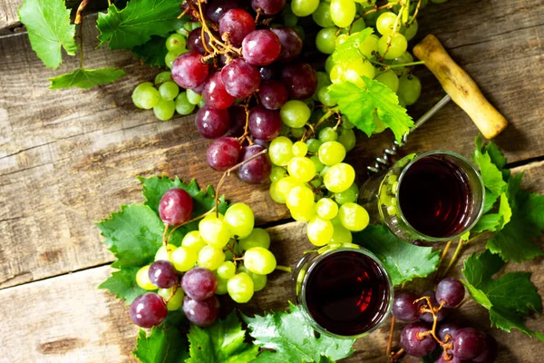 Wine concept. Red wine in glasses, bottle, grapes on vintage bac