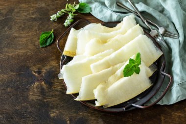 Taze kavun rustik ahşap masada parçalara dilimlenmiş. Boş alan