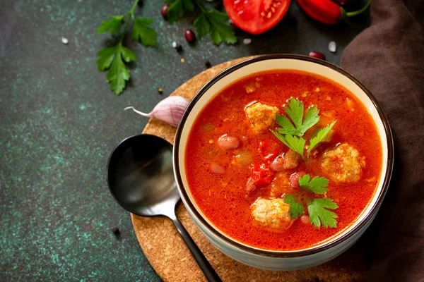 Soupe de tomates avec boulettes de viande et piments sur une pierre foncée ou — Photo