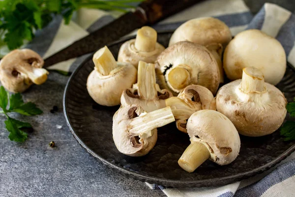 Champinjoner. Färsk vit svamp i skål på sten bakgrund. — Stockfoto