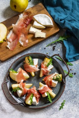 Yaz atıştırmalıkları. Jamonlu armut aperatifi, roka ve brie peyniri. Üst görünüm düz arkaplan. 