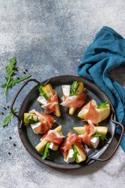 Yaz atıştırmalıkları. Jamonlu armut aperatifi, roka ve brie peyniri. Üst görünüm düz arkaplan. Boşluğu kopyala