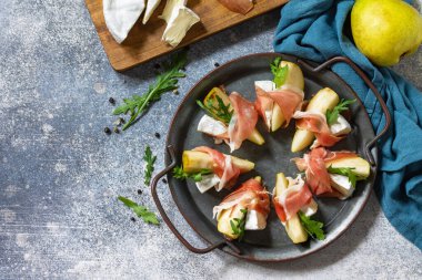 Yaz atıştırmalıkları. Jamonlu armut aperatifi, roka ve brie peyniri. Üst görünüm düz arkaplan. Boşluğu kopyala