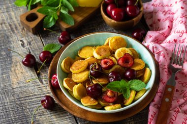 Küçük krep kahvaltısı. Kirazlı mini krep ve ahşap masa üzerinde bal. Boşluğu kopyala.