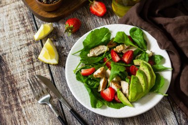 Keto için öğle yemeği. Çilekli yaz salatası, kızarmış tavuk ve kırsal bir masada avokado. Boşluğu kopyala.