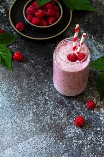 Summer cool milkshake. Raspberry protein shake in glass on a dark background. Copy space.