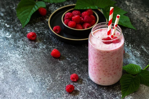 Summer cool milkshake. Raspberry protein shake in glass on a dark background. Copy space.