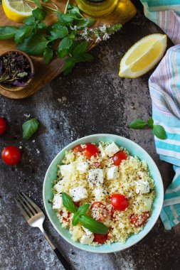Doğu mutfağı. Kuskus, domates, feta peyniri, fesleğen, biber ve zeytinyağlı sağlıklı salata. Üst görünüm düz arkaplan. Boşluğu kopyala.