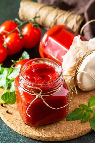 Tomato paste. Fresh tasty tomato sauce with ripe tomatoes and basil on a stone or slate background.