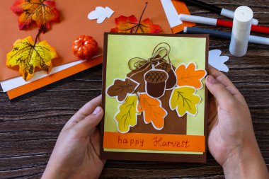 Çocuk Şükran Günü için tebrik kartını ahşap bir masada tutuyor. Çocuk sanat projesi, el yapımı, çocuklar için el işi..