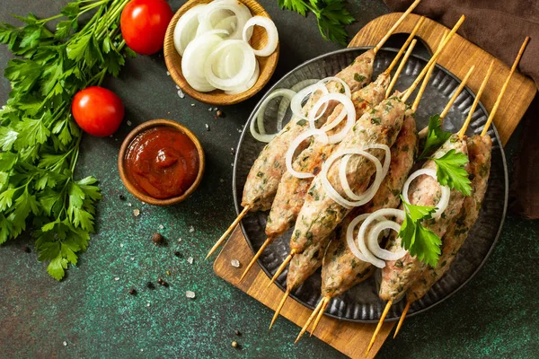 トルコのケバブ 自家製のコフタケバブは 野菜やソースを石やスレートの背景に串に刺します トップ表示フラットレイアウトの背景 — ストック写真