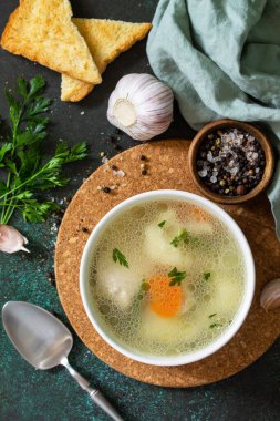 Sebzeli tavuk çorbası ve siyah taş bir masa. Üst görünüm düz arkaplan.