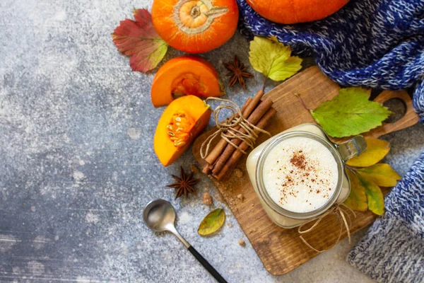Autumn pumpkin spiced latte or coffee in glass with organic ingredients on a light stone countertop. Top view flat lay background. Copy space.