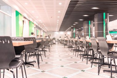 Modern interior of cafeteria or canteen with chairs and tables, eating room in selective focus clipart