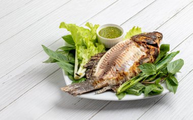 Izgara Tilapia tatlı su balığı. Lezzetli Tayland yemeği. Beyaz tabakta yeşil sebze.