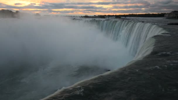 Vista oscura del agua de las Cataratas del Niágara en oposición a las nubes rosadas del amanecer temprano — Vídeo de stock