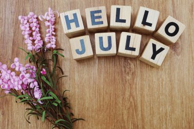 Merhaba Temmuz ile ahşap arka plan üzerinde yapay çiçek