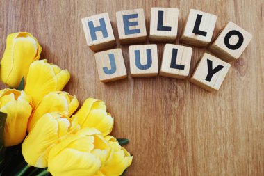 Merhaba Temmuz alfabesi harfleri ve lale yapay çiçekler Buket ahşap arka plan üzerinde