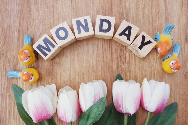 Pazartesi alfabesi ile ahşap arka plan üzerinde yapay çiçek