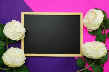 yazı tahtası ve demet güller çiçek pembe ve mor arka plan düz üzerinde yatıyordu