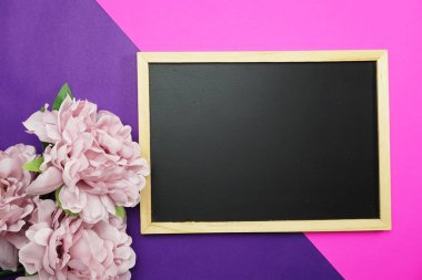 yazı tahtası ve demet Şakayık Çiçeği pembe ve mor arka plan düz üzerinde yatıyordu