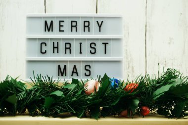 oyuncak ayı ve yeşil tinsel dekorasyonu ile ışık kutusu üzerinde neşeli Noel kelime