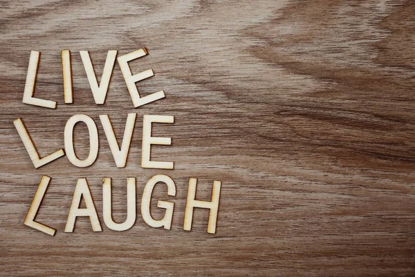 Live Love Laugh text massage on wooden background