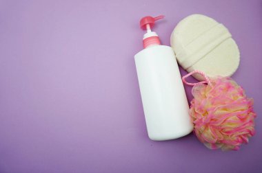 Mor arka plan üzerinde duş puf ve saç fırçası ile Düz yatıyordu banyo ürünleri duş şişesi