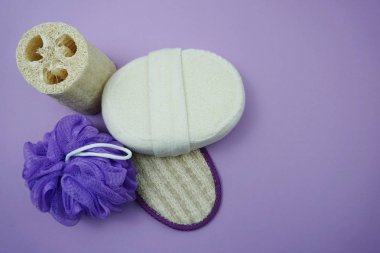 Mor arka plan üzerinde duş puf ve saç fırçası ile Düz yatıyordu banyo ürünleri duş şişesi