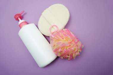 Mor arka plan üzerinde duş puf ve saç fırçası ile Düz yatıyordu banyo ürünleri duş şişesi