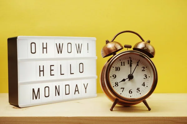 Hello Monday text in light box with alarm clock on Yellow background