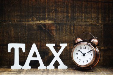 Tahta arka planda vergi konsepti vergi alfabesi harfleri ve alarm saati ödeme zamanı