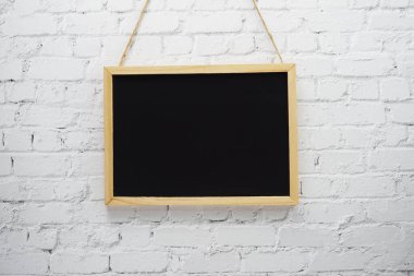 Beyaz tuğla duvar arka planında boş siyah tahta