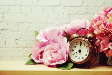 Beyaz tuğla duvar zemininde çiçek süslemeli çalar saat