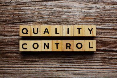 Ahşap arkaplanda Kalite Kontrol alfabesi harfi