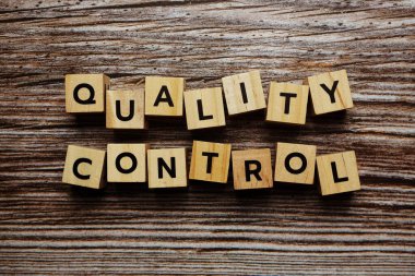 Ahşap arkaplanda Kalite Kontrol alfabesi harfi