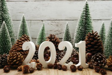 Yeni yılınız kutlu olsun. Ahşap zemin üzerinde Noel ağacı ve çam kozalağı süslemesi olan şenlikli bir geçmiş.