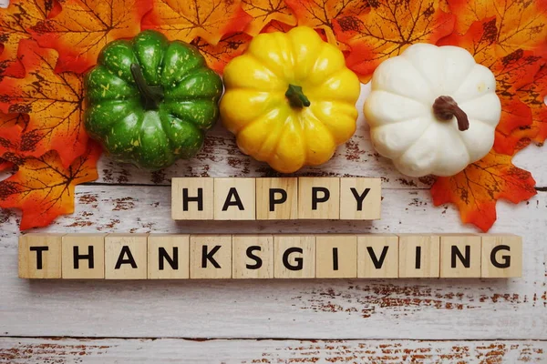 Happy Thanksgiving alphabet letter with pumpkins and autumn leaves on wooden background