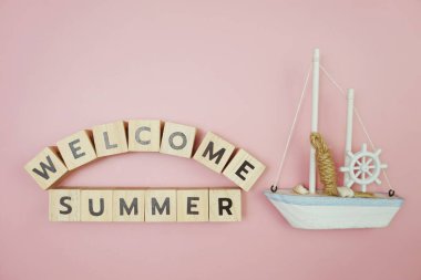 Hoş geldiniz. Pembe arka planda yelkenli teknesi olan yaz mesajı alfabesi mektubu.