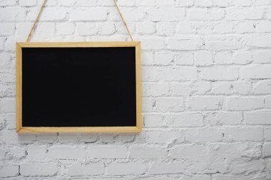 Beyaz tuğla duvar arka planında boş siyah tahta