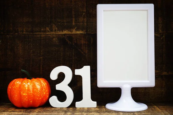 Blank Display frame stand with orange pumpkin on wooden background